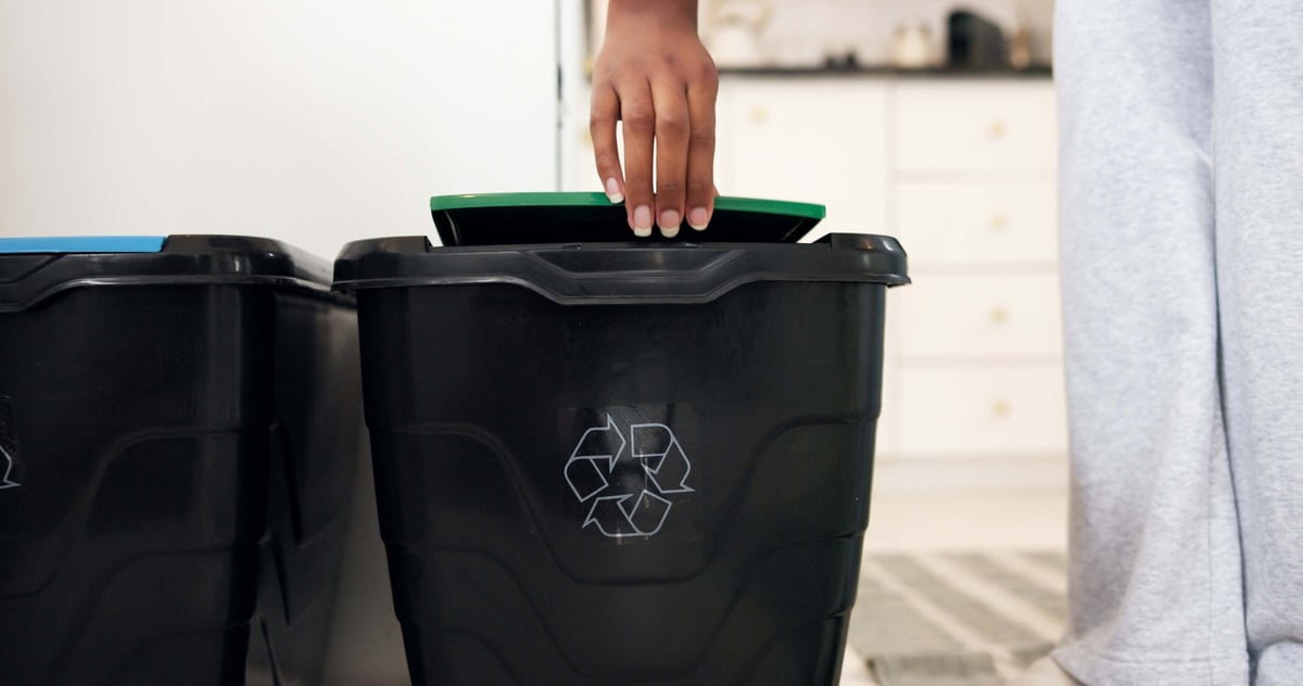 Person sorting recyclables into a home recycling bin